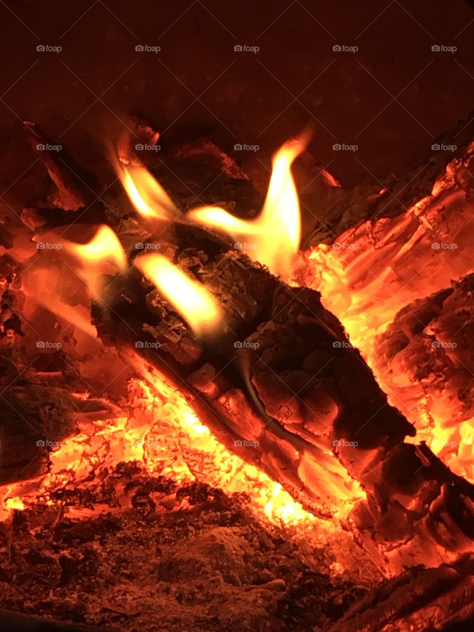 Pile of wooden logs burning with flames in a chiminea in the garden