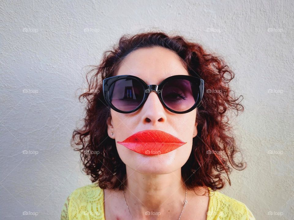 funny and crazy portrait of a woman with red fleshy leaf instead of lips