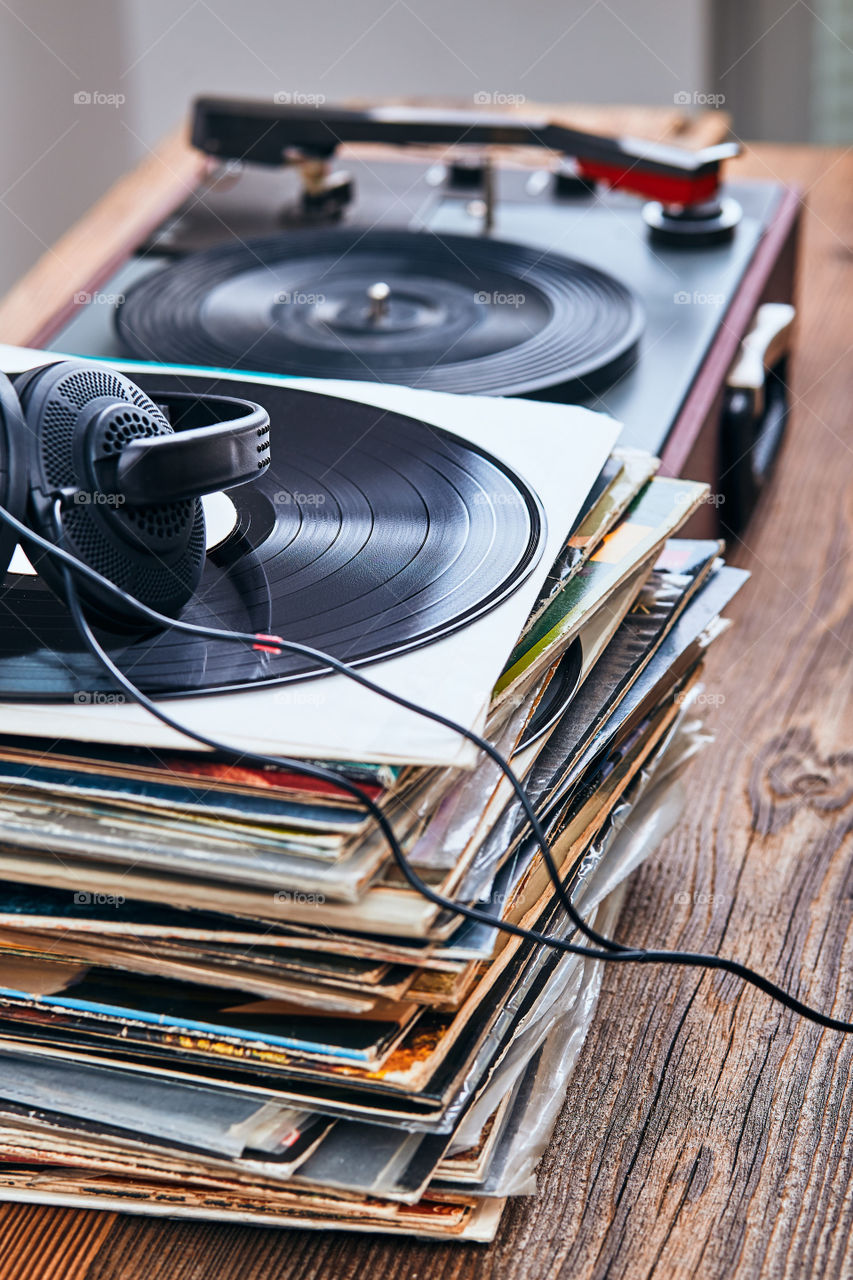 Stack of many black vinyl records, turntable vinyl player and headphones put on the stack. Classic stereo set. Candid people, real moments, authentic situations