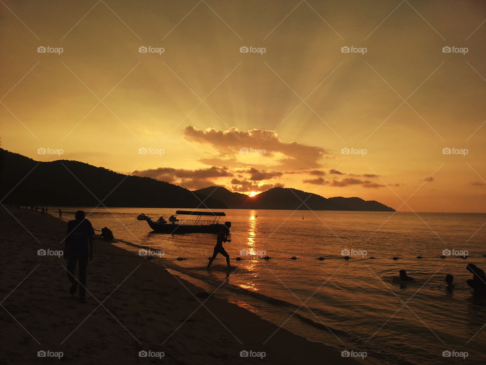 Breathtaking landscape orange sunset view with silhouettes of boat, hills and people enjoying the moment