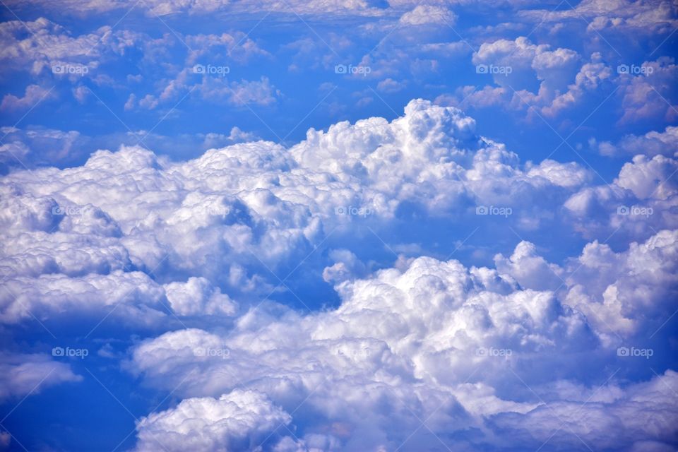 aerial view on fluffy clouds on the blue sky from plane window