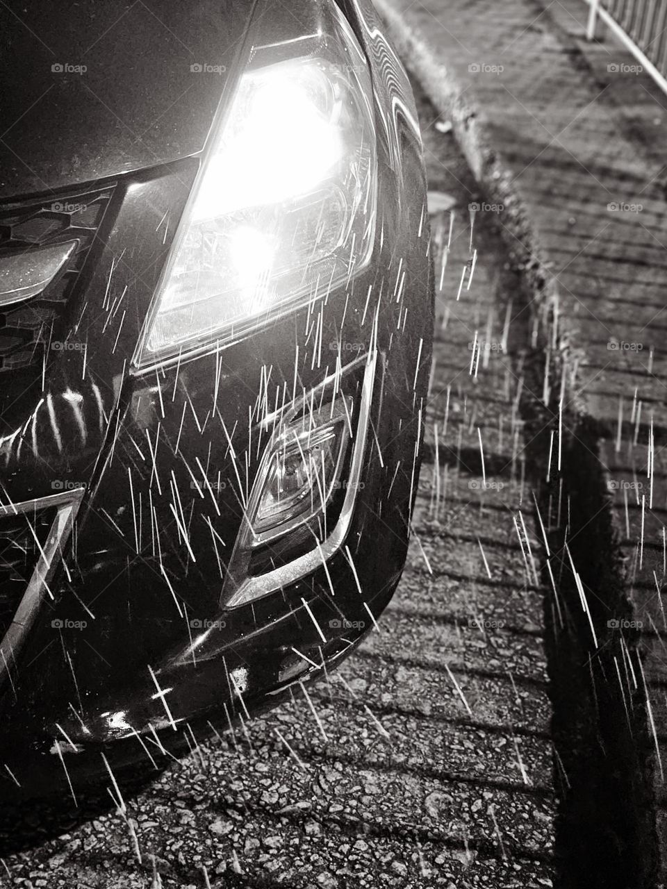 Car with headlights on on a rainy night