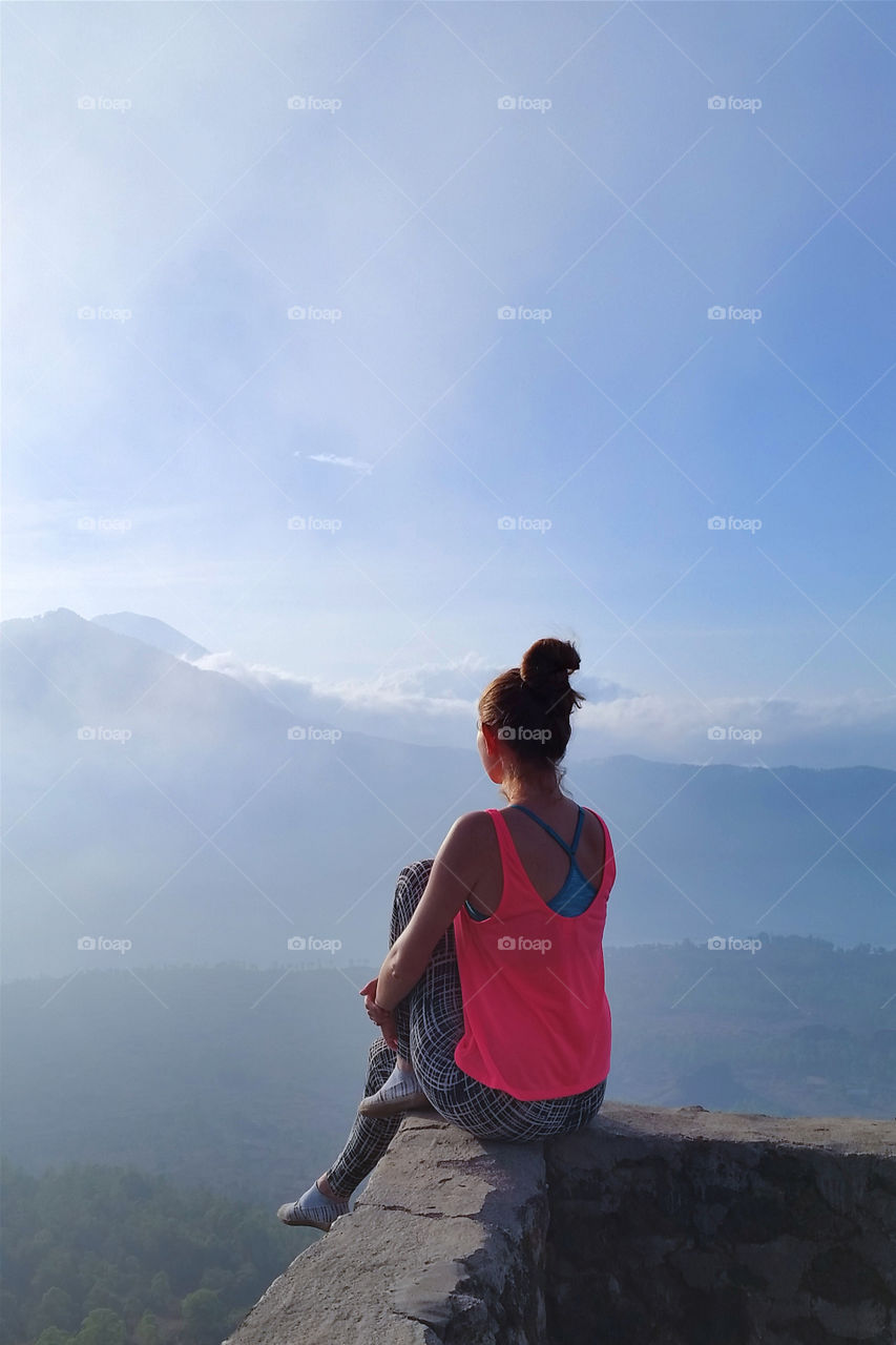 Young millennial woman enjoying the view at the top of the mountain in Bali
