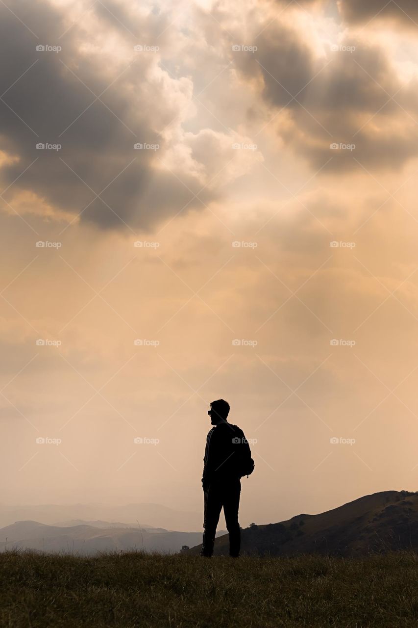 Silhouette of male hiker in field against sky.