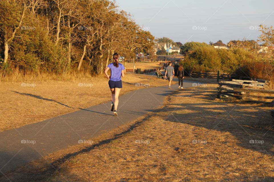 Young woman running on a path on sunset