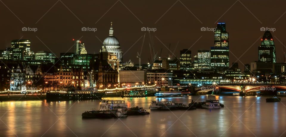 The bright lights of London reflect in the River Thames at night, as viewed from Waterloo Bridge 