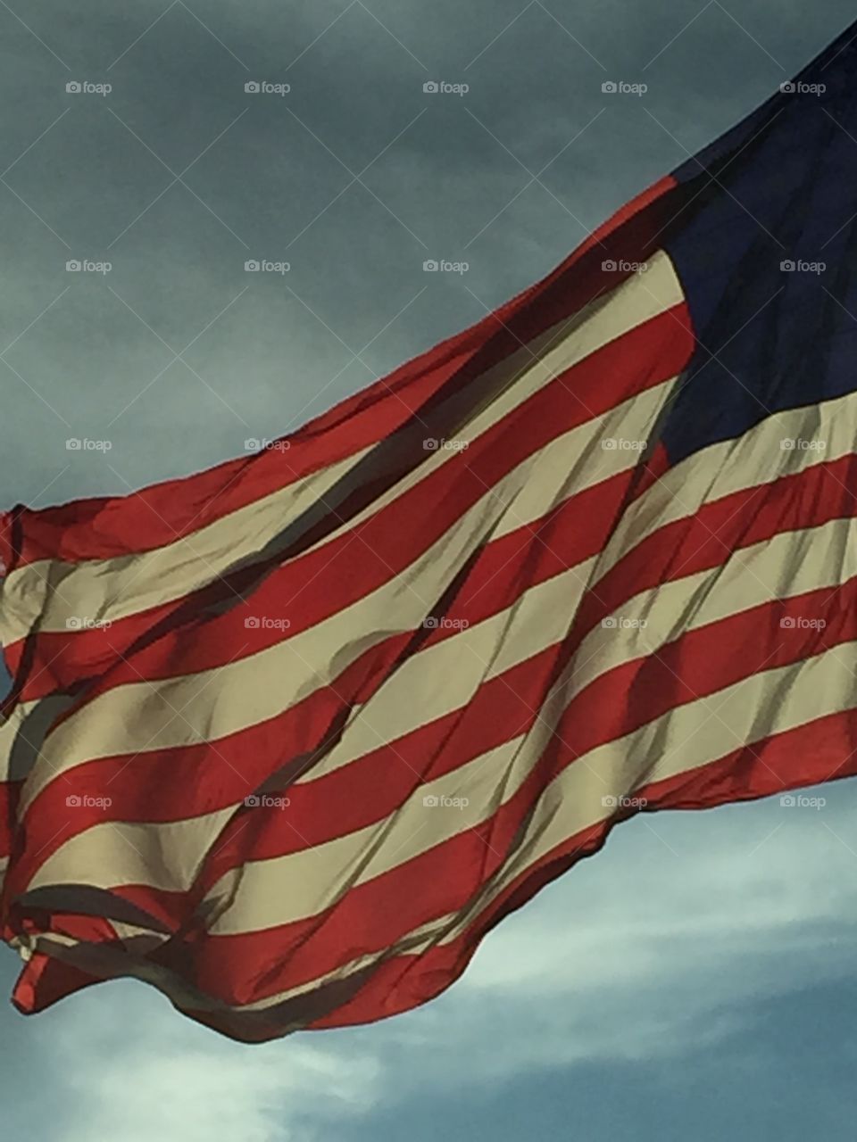 Huge closeup of American flag flying against the sky.
