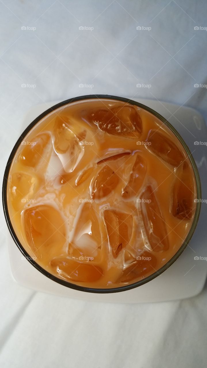 A glass if sweet Thai Iced Tea topped with creamy milk