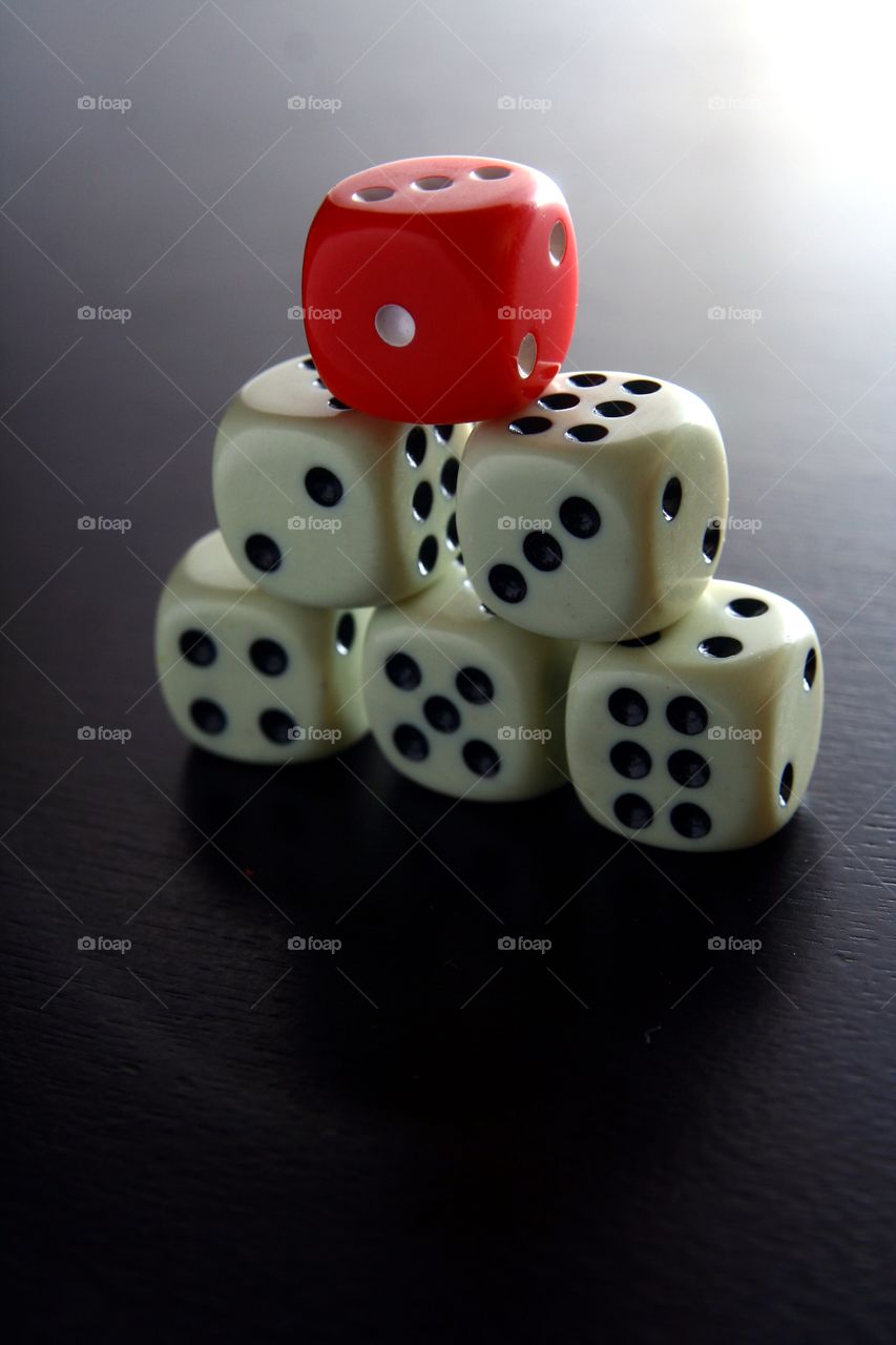 red and white game dice. 1 red game dice on top of stacked 5 white game dice