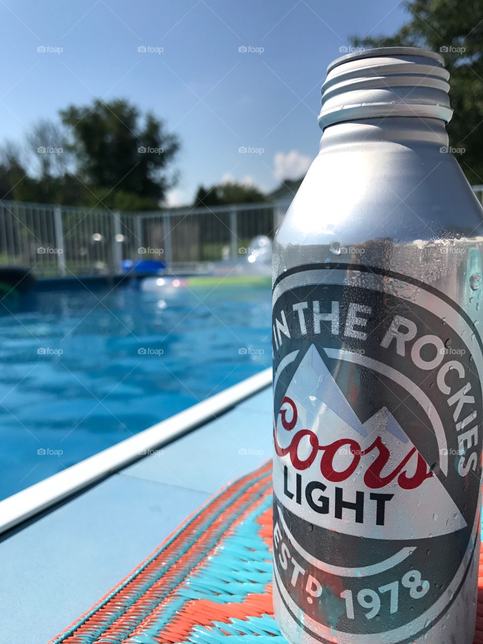 Bottle of Coors Light beer sitting by swimming pool