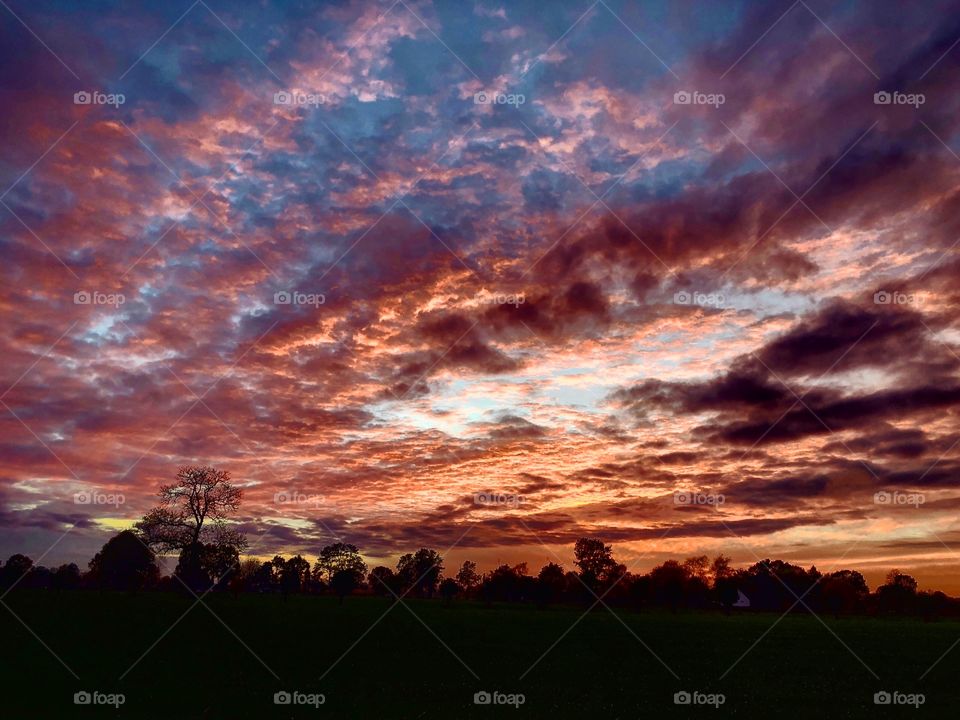 Dramatic and colorful rolling clouds in the sky over the silhouettes of a rural Countryside landscape 