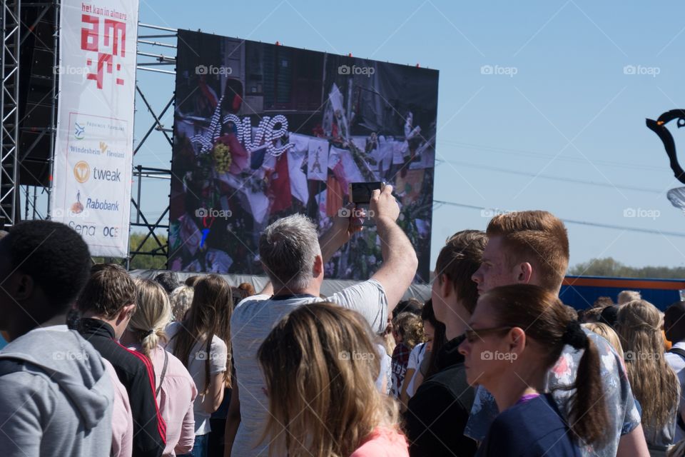 An adult man taking a picture of the crowd during a festival
