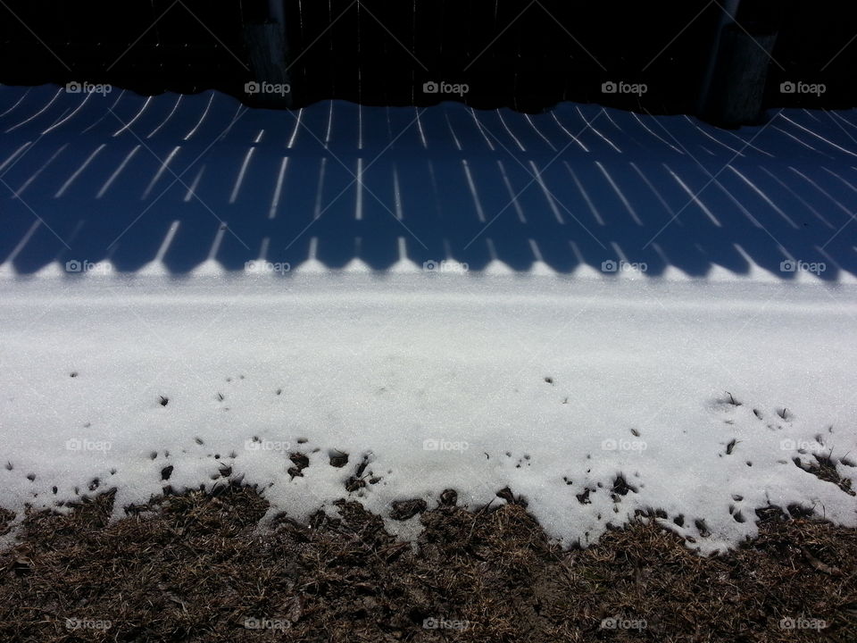 Shadows on snow. Shadow of a fence on snow drift