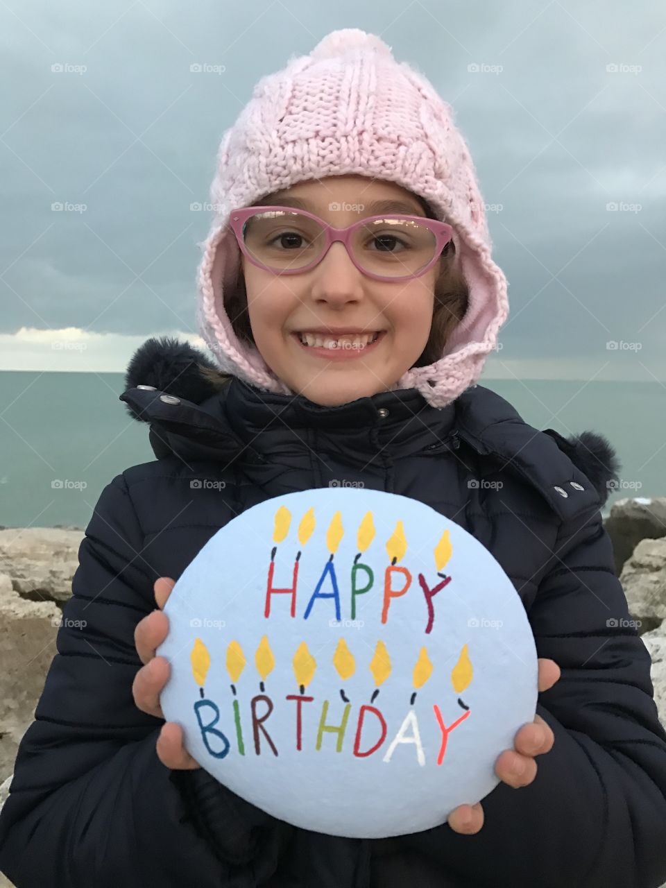 Portrait of happy girl holding text written pebble stone