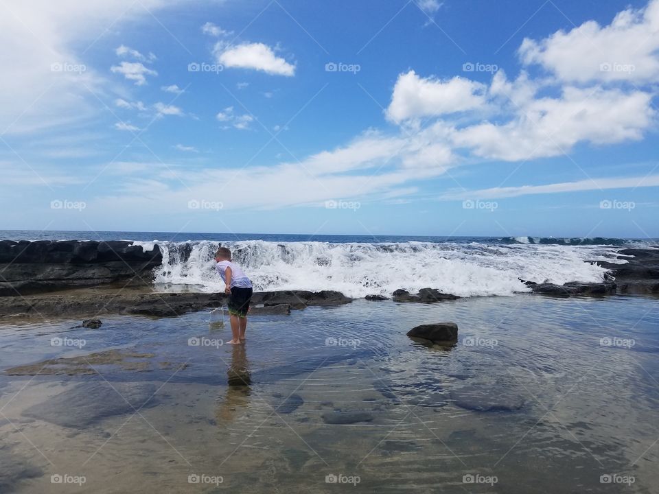 Boy watches waves crash over old lava beds