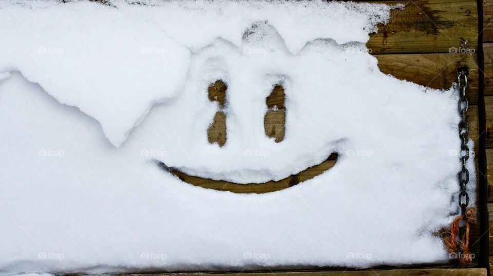 snow on a wooden door with smiley face