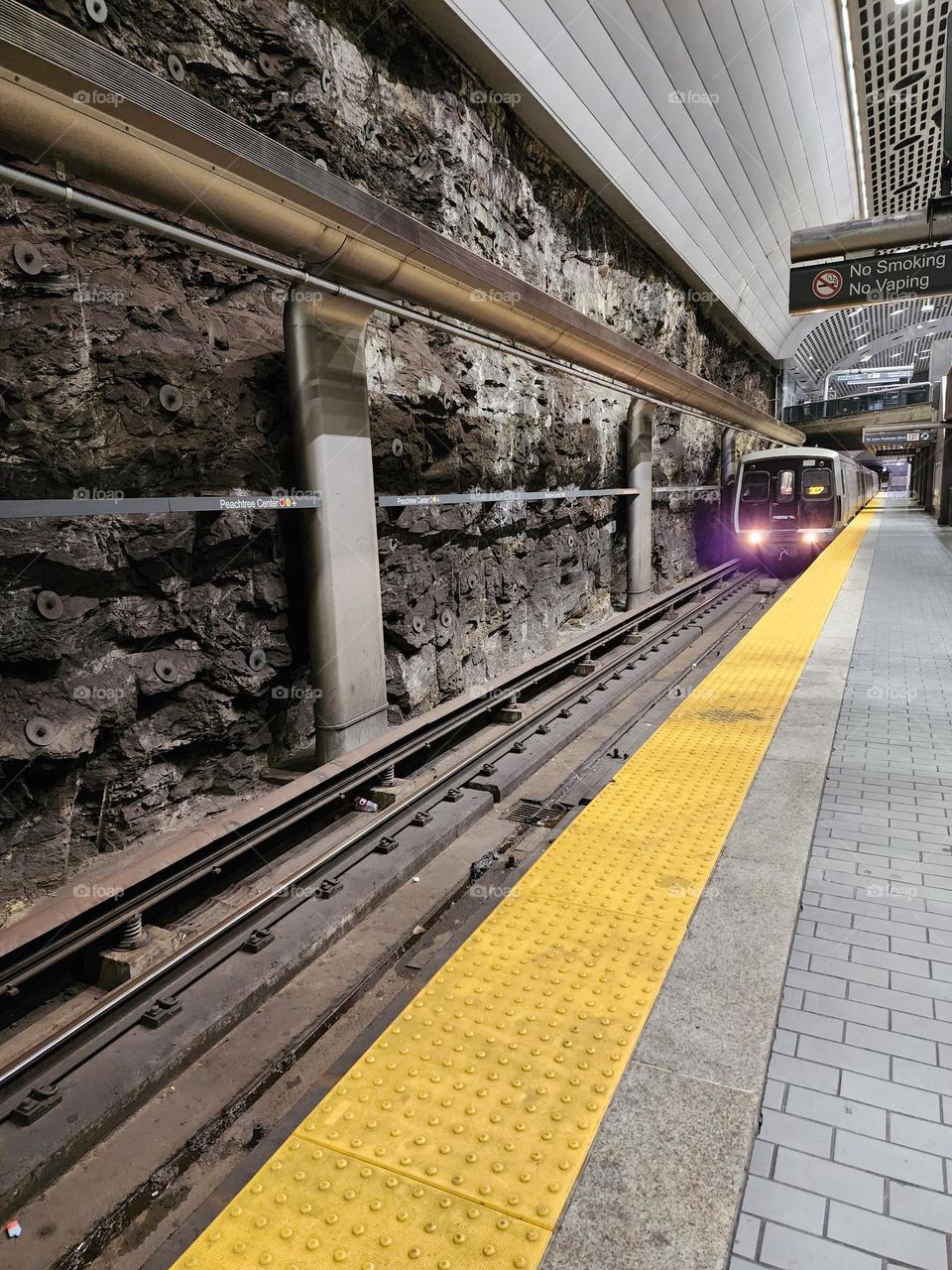 A subway train arrives to pick up passengers in a dark cave like station