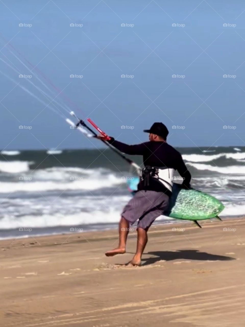 Man preparing to enter the sea with a kitesurfing board