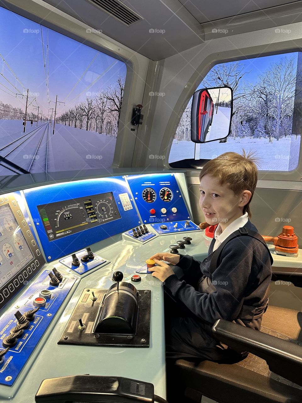 Child red-haired boy has fun on the simulator become a train driver