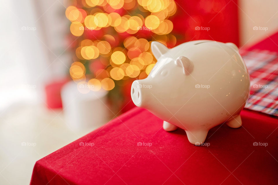 piggy bank with 100 dollars banknote in festive New Year atmosphere of scenery. Magical bokeh with Christmas tree and bright lights.