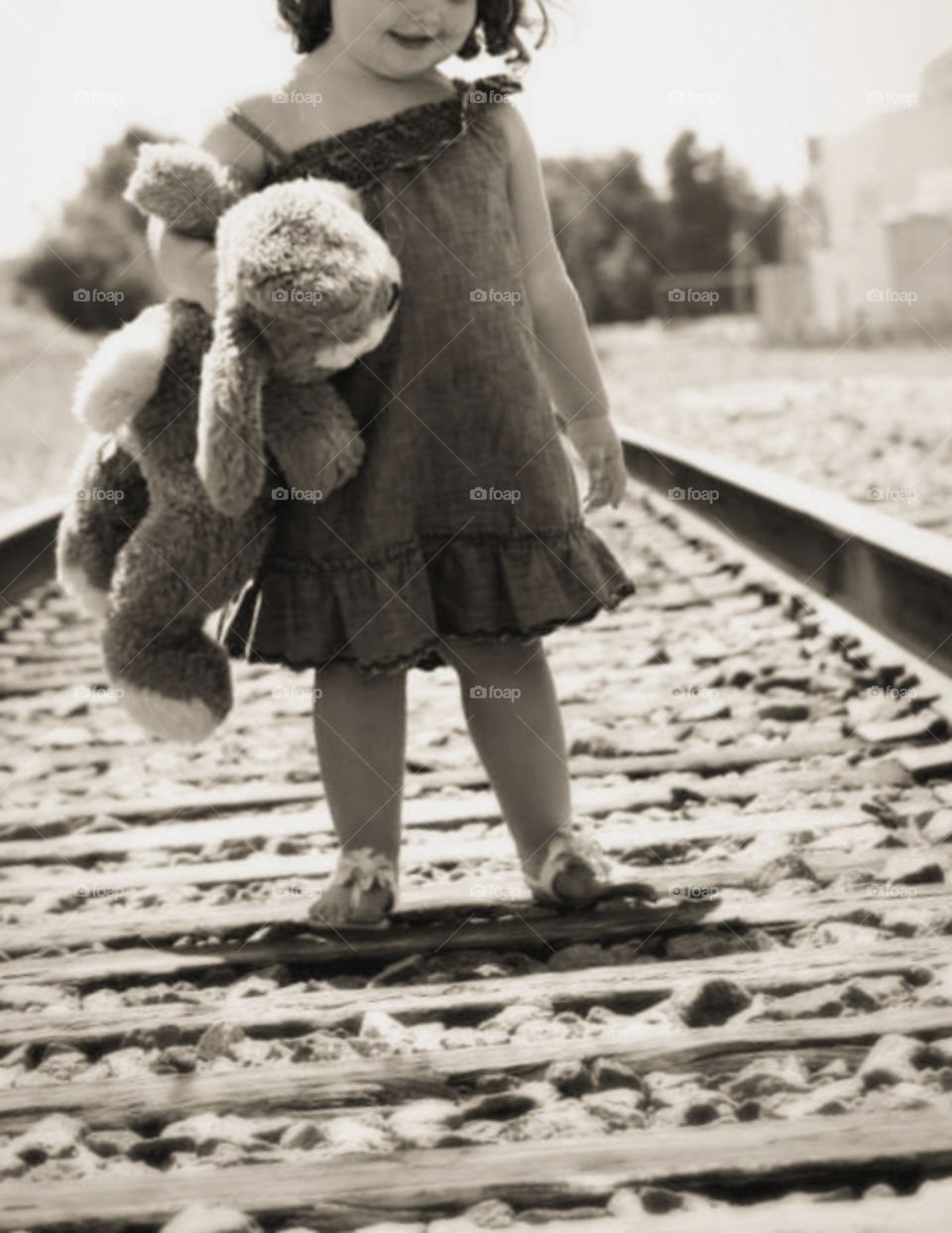 Little Girl standing on train tracks holding a stuffed animal. vintage. old soul