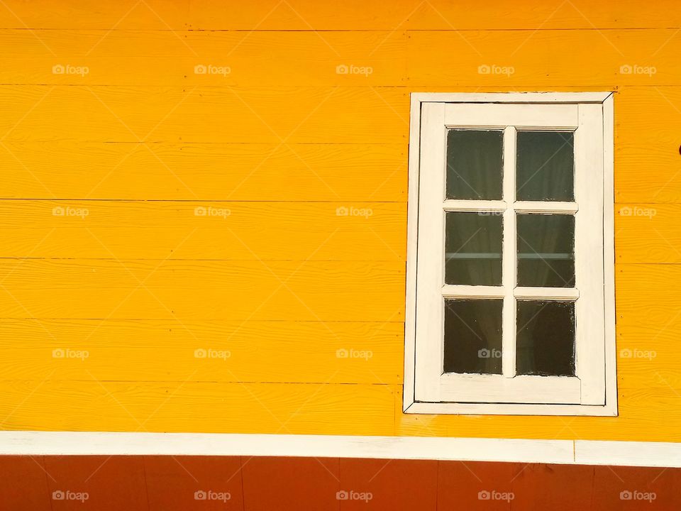 One white window on the yellow wall.