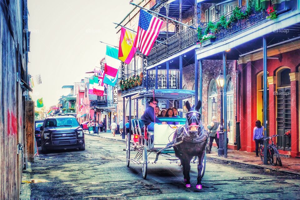 Horse drawn carriage carrying tourists through a street in the French Quarter, New Orleans, Louisiana, USA.