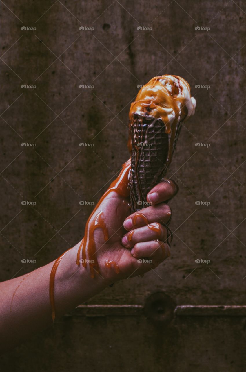 ice cream cone hand dripping caramel sauce vanilla chocolate sauce close up textural 