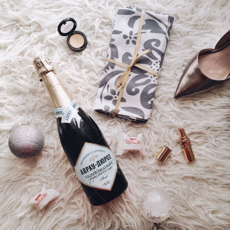 Champagne bottle, cosmetics and silver heels flat lay. Getting ready for a party!