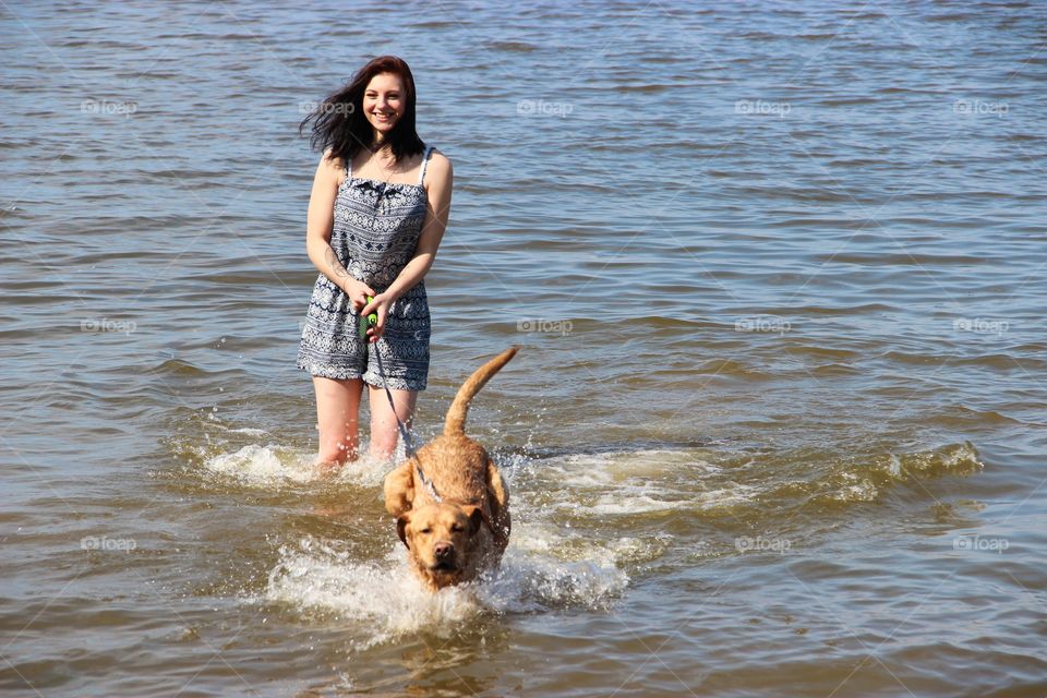 Young woman playing with dog in sea