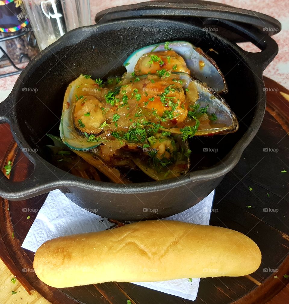 Delicious tantalizing mussels soaked in white wine and garlic served with butter bread roll