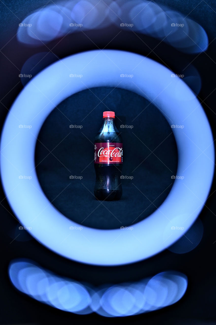 Close up shot of two Coca Cola with black background with the mists at the studio, with light rings. 
