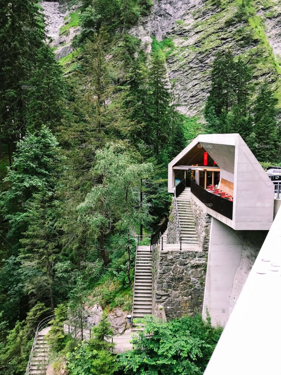 A stop in for sightseeing in a famous canyon in Switzerland. The white place is to sell admission tickets , then there are many step to go down, besides there are many green trees and Cliff
