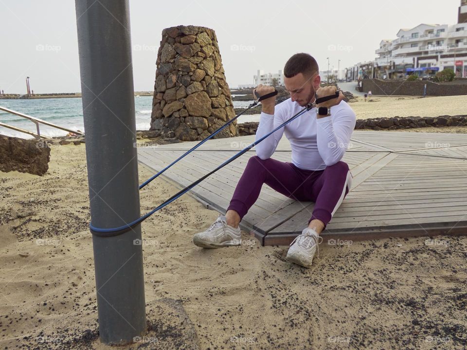 chico joven entrenando en la calle en exteriores, usando bandas elásticas y realizando ejercicios variados