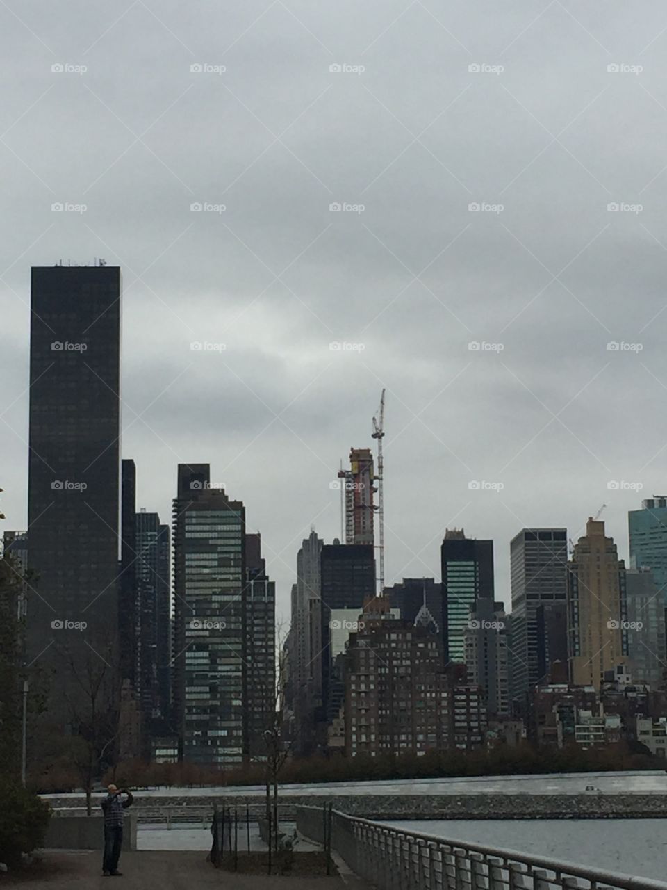 Photo of Manhattan's skyscrapers and winter sky. You can see the architecture and the river.