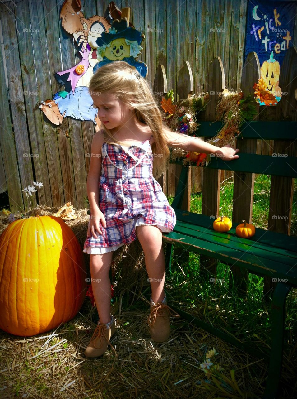 Cute girl sitting with pumpkin on bench