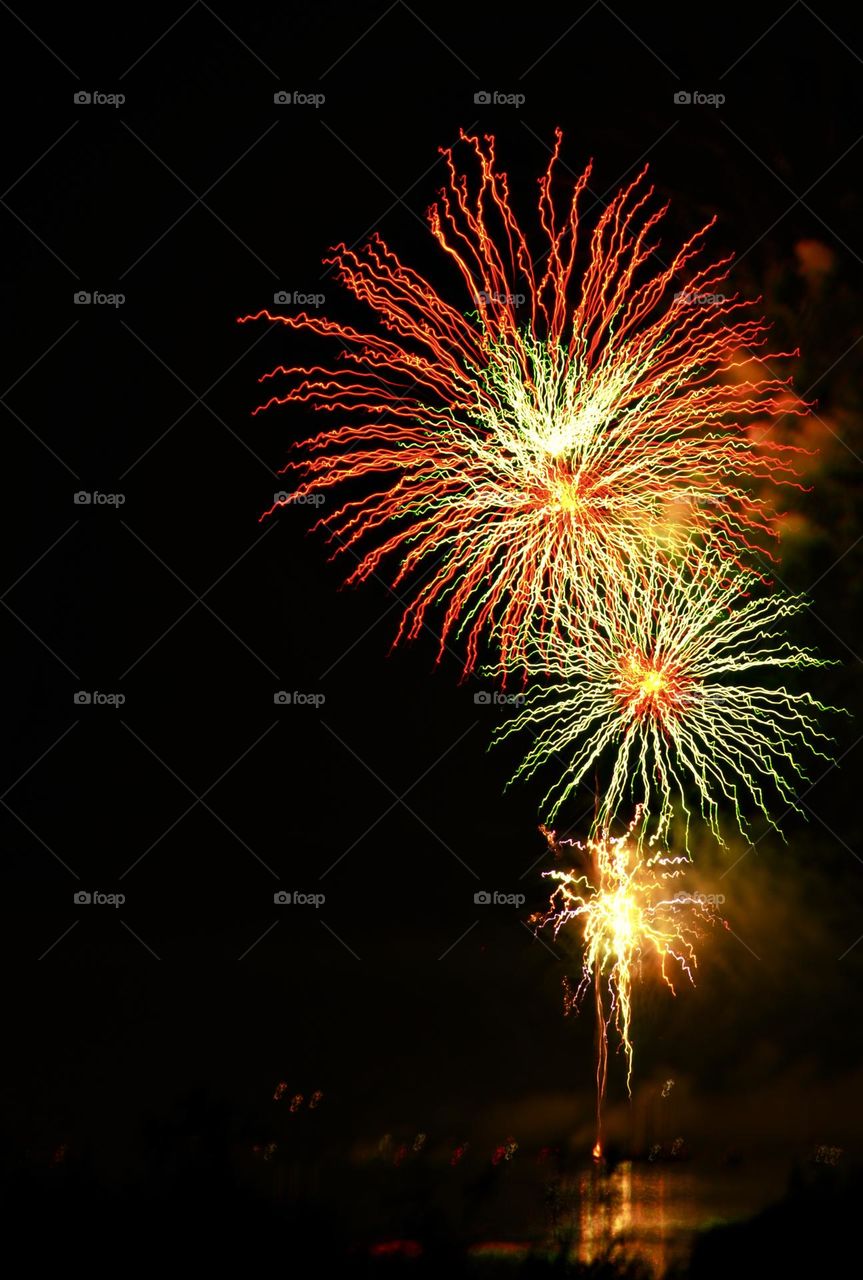 Fourth of July celebration - A colorful and bright explosion of light patterns created by fireworks against a dark sky, with reflections visible on the water