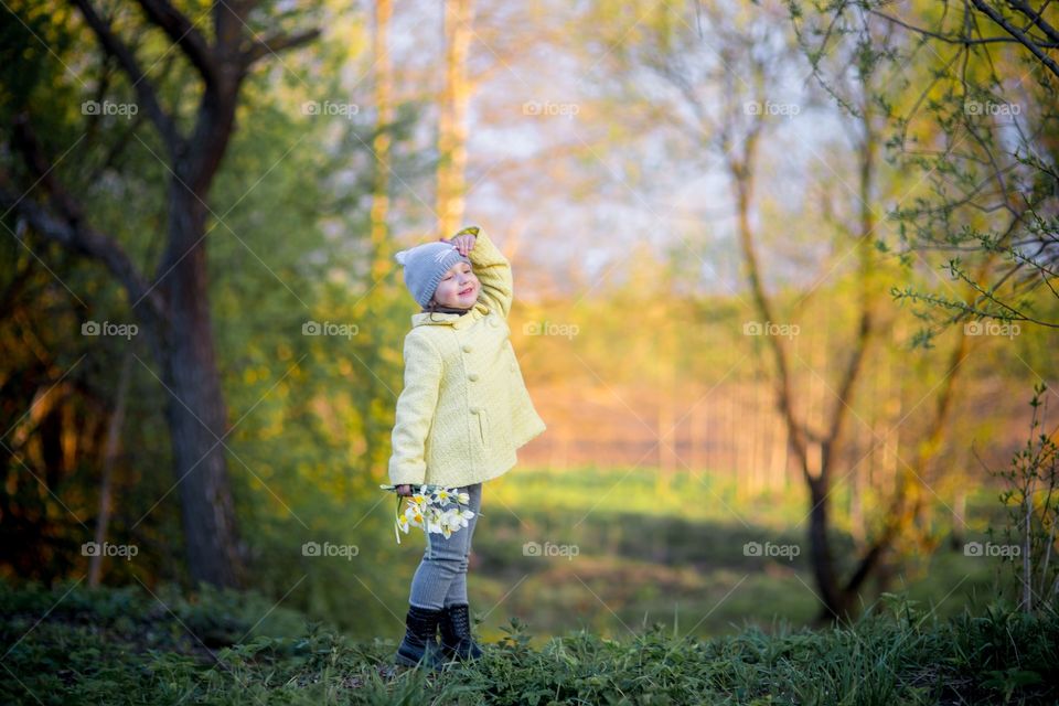 Little girl with narcissus bouquet in spring park