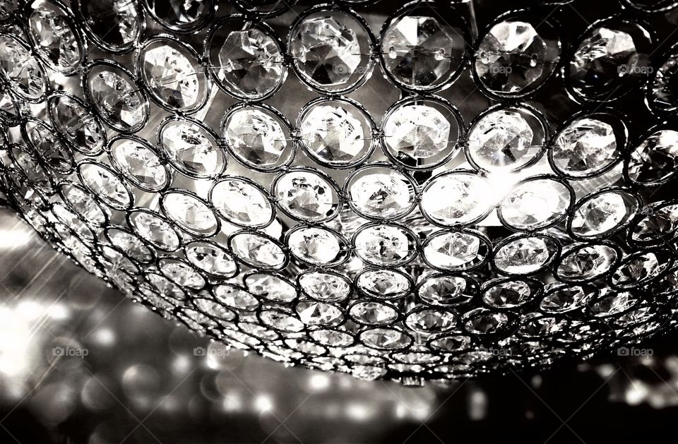 Bright white light rays shine through the prisms of a chandelier.