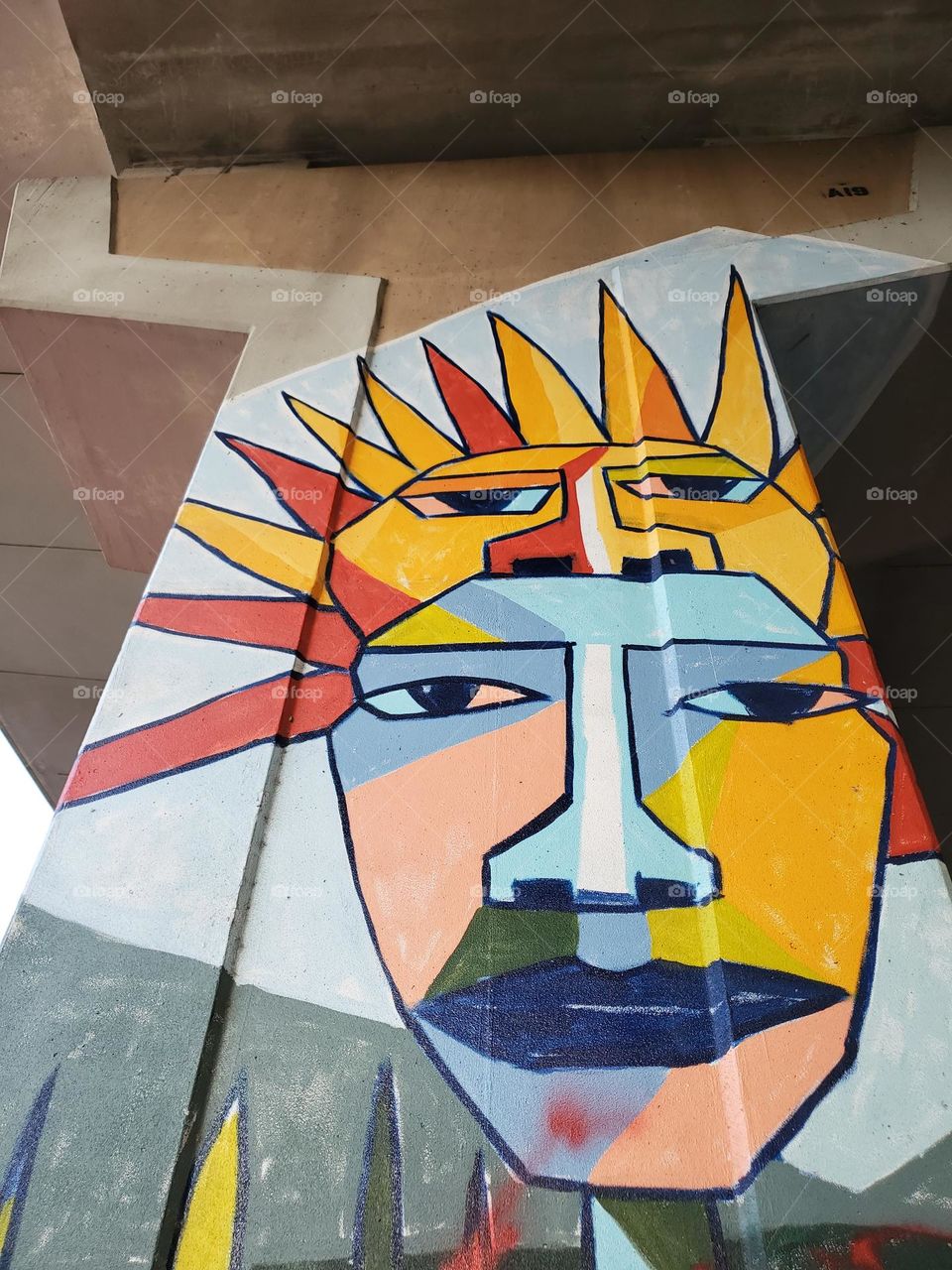 Street art on cement Highway pillar. Colorful block style painting of a man with a sun peering out from behind.