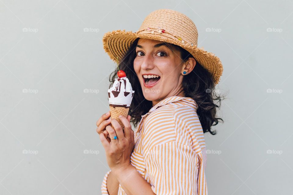 Young millennial woman, being happy and smiling while eating a delicious icecream, during a summer day.