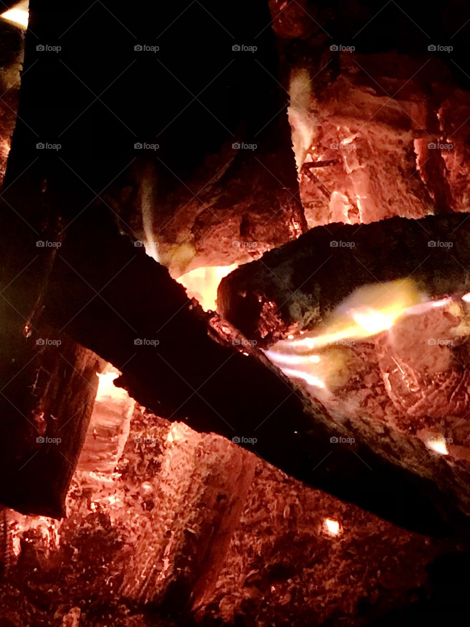 A closeup of logs burning in a fire with flames all around