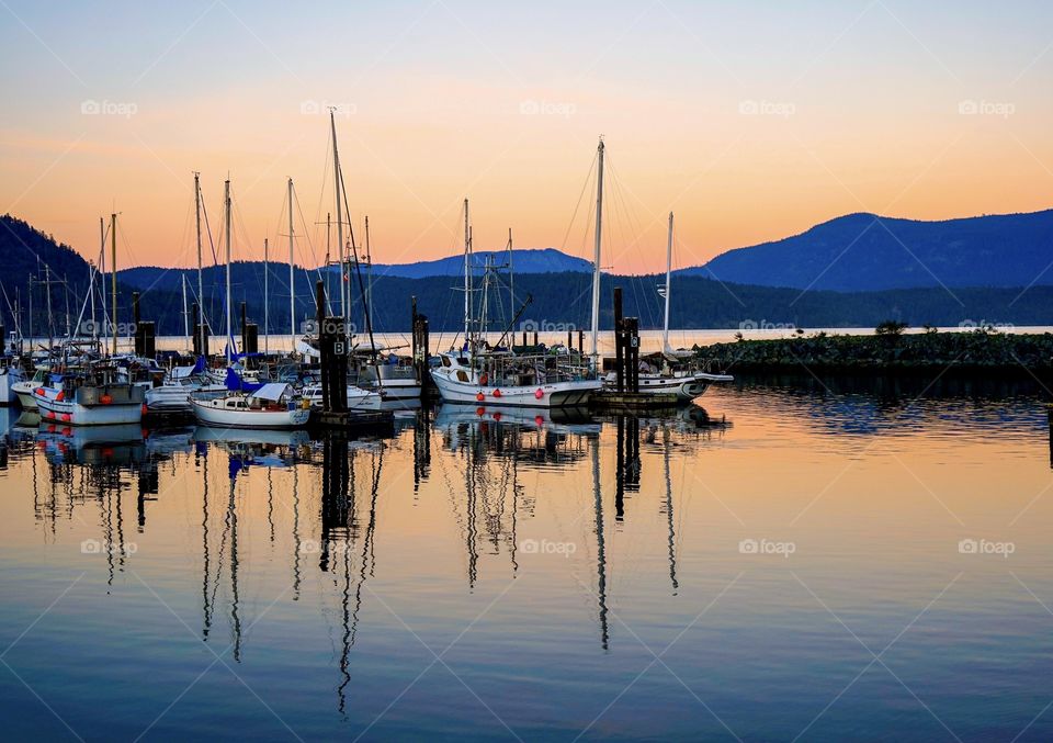 Boats reflected on silent ocean at sundown - marina on Pacific coast 