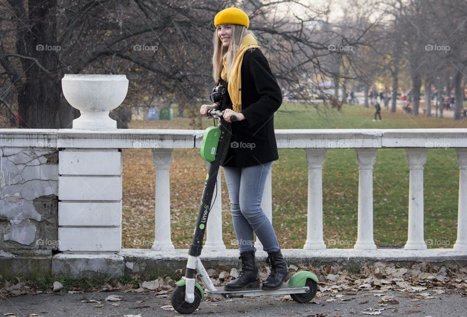 Beautiful young woman on scooter in the park