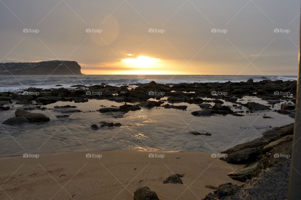 Tidal rocks at beach during sunset
