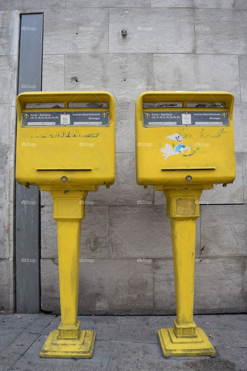 Yellow mailboxes stand out against a concrete wall in Paris, France. October 2016.