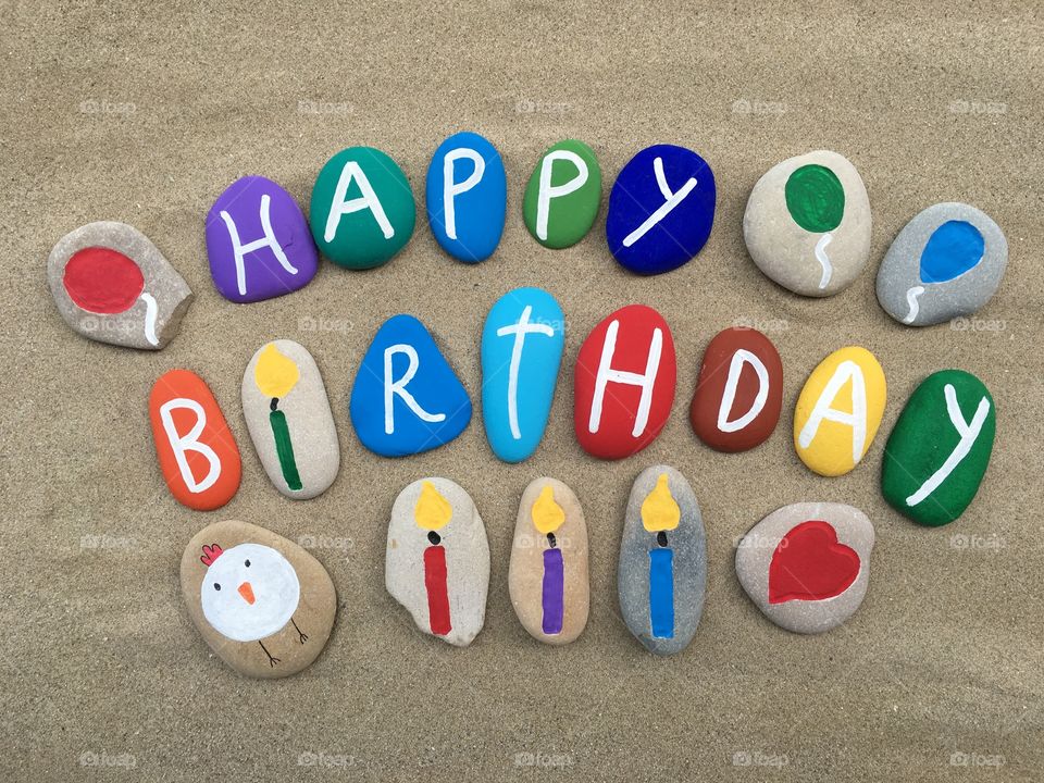 Happy Birthday, multicolored stones design on the sand 