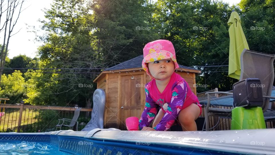 little girl drinks water from the pool.