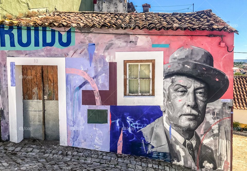 Mural of Portuguese painter José Malhoa by Frederico Draw + Contra, on the side of a building in the cobbled streets of Figueiró dos Vinhos, Portugal