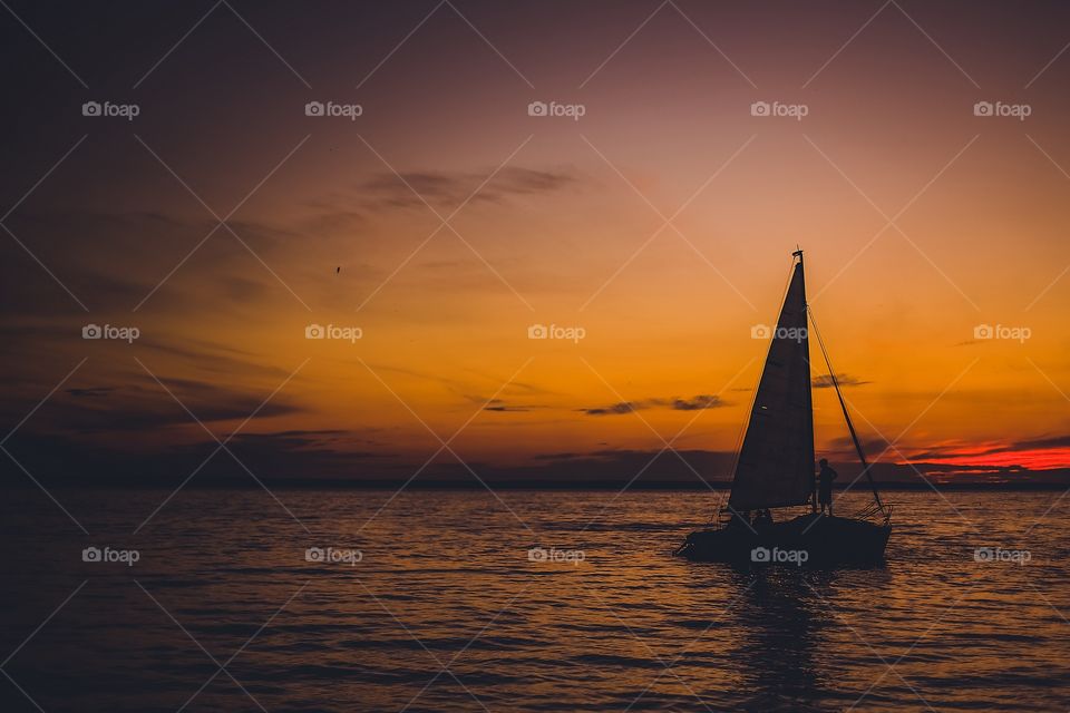 Silhouette of sailboat in the sea at sunset
